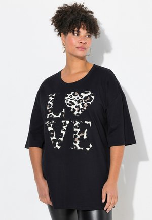 T-shirt noir surdimensionné arborant "LOVE" en lettres gras, avec un cœur et des accents de lettres en imprimé léopard. Manches courtes, coupe décontractée.