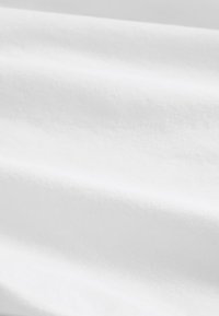 Close-up view of smooth white fabric with subtle folds and soft texture.
