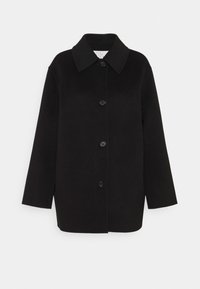 Černý oversized kabát vyrobený z měkké látky, s velkým límcem, předním zapínáním na knoflíky a dvěma náprsními kapsami. Čistý, minimalistický design.