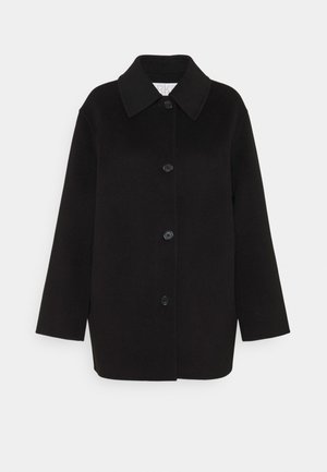 Zwarte oversized jas van zacht stof, met een grote kraag, sluiting met knopen aan de voorkant en twee borstzakken. Schoon, minimalistisch ontwerp.