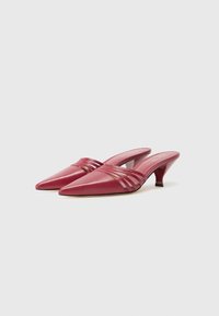 Punaiset nahkaiset slingback-korkokengät, joissa on terävä kärki, ja joissa on raidallisia yksityiskohtia etuosassa sekä kohtuullisen kaareva korko.