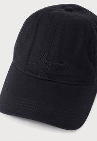 Gorra negra de algodón con visera curvada, con un logo bordado en tono sobre tono en la parte frontal y detalle de costuras a lo largo de la visera.