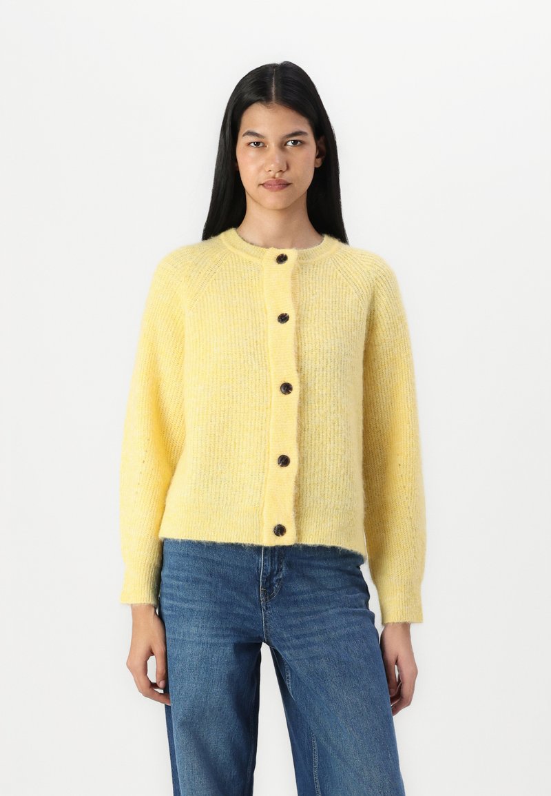 Cardigan en tricot jaune avec un col rond, des manches longues et des boutons marron. Texture douce et design légèrement court.