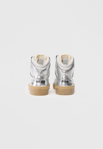 Zapatillas altas plateadas con cuero texturizado, forro interior blanco y suela de goma. Presenta una marca en la parte posterior y en el lateral.