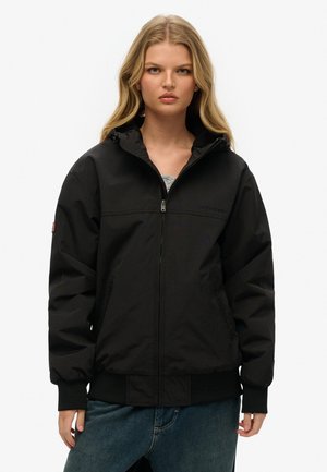 Zwarte hoodiejack gemaakt van gladde stof, met een rits aan de voorkant, twee zijzakken en ribgebreide manchetten en zoom.
