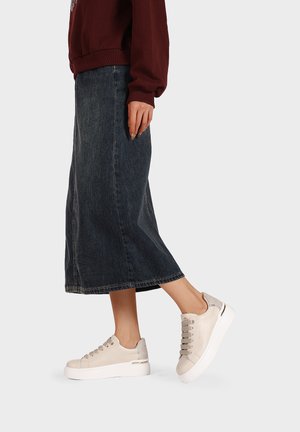 Sneakers beige con dettagli in pelle testurizzata e tessuto, punta tondeggiante e suola bianca. Indossati con una gonna di jeans scura e una felpa bordeaux.