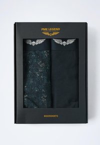 Boîte-cadeau noire contenant deux paires de boxers. Une paire présente un motif floral sombre, tandis que l'autre est de couleur noire unie, les deux avec une ceinture de marque.