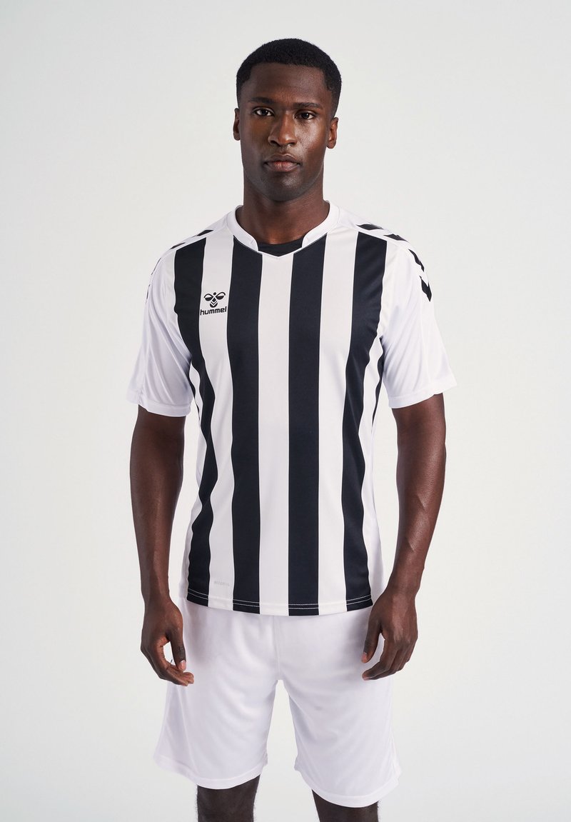 Maillot de football noir et blanc à rayures avec des manches courtes, design en V, et logo sur la poitrine, associé à un short blanc.