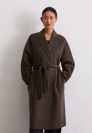 Cappotto in misto lana marrone con chiusura doppiopetto, ampi rever e cintura legata. Presenta bottoni grandi e tasche laterali.