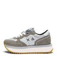Zapatilla gris y blanca con materiales de gamuza y tela, que presenta detalles en negro, una suela texturizada y diseños geométricos en los laterales.