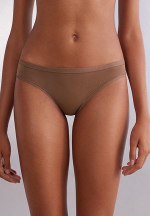 Tan bikini-achtige lingerie met een gladde textuur, minimalistisch ontwerp en elastische tailleband, geplaatst tegen een neutrale achtergrond.