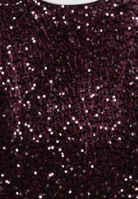 Tessuto borgogna ricoperto di paillettes rotonde lucide, creando una superficie texturizzata che riflette la luce e aggiunge interesse visivo.
