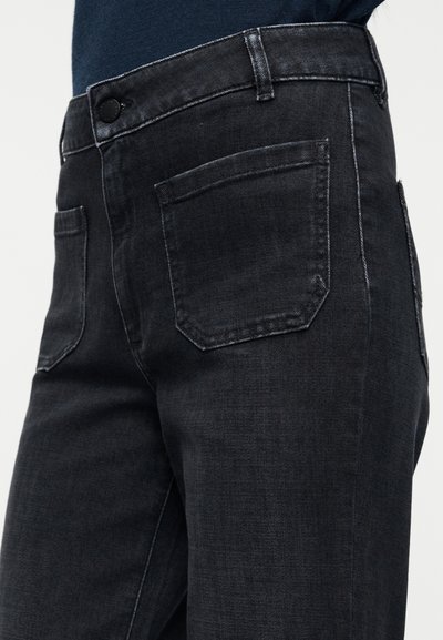 Σκούρο τζιν με εφαρμοστή γραμμή, με κούμπωμα με κουμπιά, τσέπες με ραφές και αντίθετες λεπτομέρειες ελαφριάς ραφής.