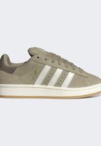 Baskets en suede gris clair avec des rayures en cuir blanc, un talon texturé et une semelle en caoutchouc. Elles disposent de sept trous de ventilation et d'un accent logo doré.