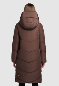 Bruine gewatteerde jas met een chevronpatroon, een grote capuchon en lange mouwen, voorzien van een logo aan de onderzijde van de voorkant. Glad stofoppervlak.