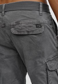 Grå cargo shorts med en strukturerad tyg, sidofickor och en bakre ficka med ett märke. Midjan är elastisk för extra komfort.