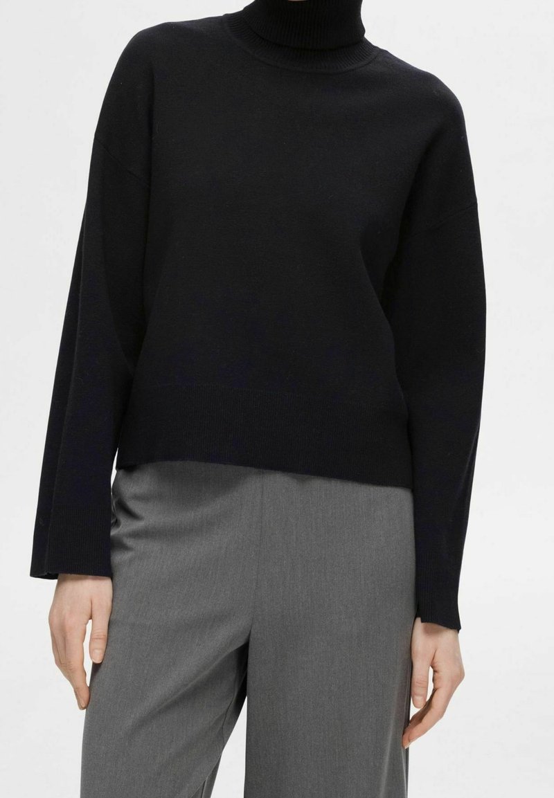 Musta poolokauluspaita, jossa rento istuvuus ja resoripintainen kaulus sekä hihansuut. Yhdistetty harmaisiin räätälöityihin housuihin.