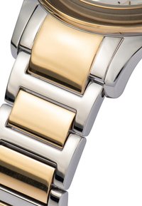 Bracciale di metallo per orologio con maglie alternate in oro e argento, caratterizzato da una superficie lucida e un design robusto e geometrico.