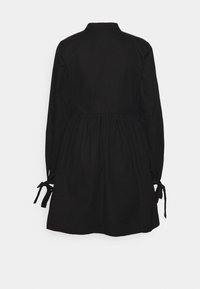 Černé bavlněné šaty s límečkem, dlouhými rukávy s detaily na zavazování a s nařaseným pasem. Hladká textura a délka po kolena.