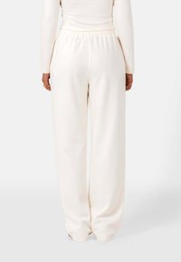 Crème-kleurige wijde broek met een elastische tailleband en een zachte textuur, met een minimalistisch ontwerp zonder zichtbare hardware of patronen.
