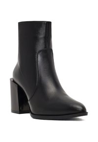 Botte noire en cuir à bout pointu et à talon épais. Elle présente une surface lisse et des coutures minimalistes.