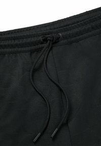 Svarta träningsshorts med en texturerad tyg, elastisk midja och justerbar dra-kord med plastspetsar.