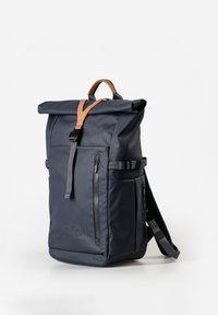 Marineblauer Rucksack mit Rollverschluss, vorderen Reißverschlusstaschen, verstellbaren Seitenträgern, gepolsterten Schultergurten und einem braunen Ledergriff oben.