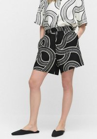 Zwart-witte short met een wervelend patroon, geweven stof, zijzakken en een elastische tailleband, gecombineerd met een bijpassend kort mouwtop.