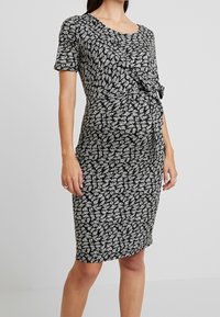 Mustahuoneinen kukkakuosiset mekko, jossa on lyhyet hihat, pyöreä pääntie ja sivusolmuysitys, joka korostaa joustavaa siluettia.