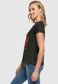Sort kortærmet t-shirt med et farverigt grafisk design på forsiden, lavet af blødt bomuldsstof, med en afslappet pasform.