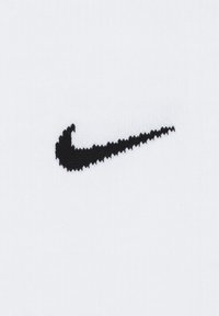 Nike-logo in het zwart op een textuur van wit stof. Het logo heeft een gebogen, swoosh-ontwerp met een gladde afwerking.