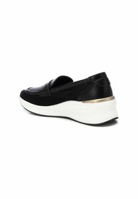 Zapato negro tipo slip-on con parte superior de cuero texturizado, detalles de malla y una suela de cuña blanca con una franja metálica dorada.