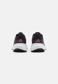 Zwarte en paarse sportschoenen met een mesh bovenwerk, een gepolsterde kraag en witte zolen met getextureerde grippatronen op de loopzool.