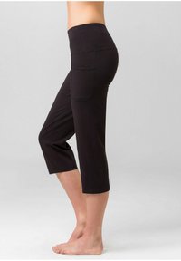 Schwarze Capri-Leggings mit einem breiten Bund und einer Seitentasche. Hergestellt aus elastischem Stoff, mit einem engen Schnitt, der an den Knöcheln zuläuft.