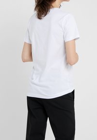 T-shirt blanc à manches courtes avec un col rond, en coton doux, présenté de dos avec une coupe décontractée.