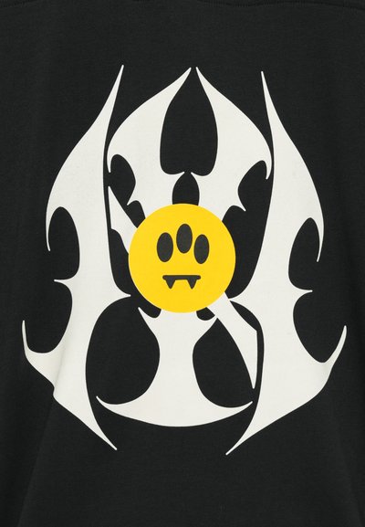 Sort bomulds t-shirt med et stort hvidt grafisk design med skarpe kanter og et gult cirkulært ansigt med tre prikker og tanddetaljer.