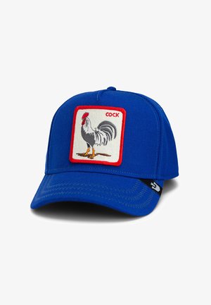 Gorra de béisbol azul con un parche bordado rectangular que presenta una ilustración de un gallo y la palabra "COCK" encima.