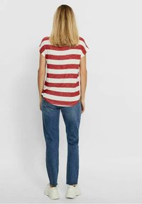 Chemise à rayures rouges et blanches à manches courtes, associée à un jean en denim bleu et des baskets blanches, vue de dos. Texture de tissu lisse.