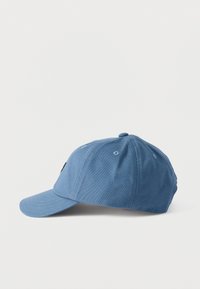 Μπλε βαμβακερό καπέλο μπέιζμπολ με ραμμένες οπές και καμπυλωτή γείσο, απεικονισμένο σε λευκή επιφάνεια σε πλευρική όψη.