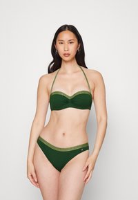 Zöld bikini redőzött szegélyű toppal és hozzá passzoló alsóval. Csillogó arany díszítéssel az élein. Simaságú anyag textúra.