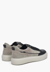 Szare zamszowe sneakersy z czarnymi skórzanymi akcentami, wiązane, z białą teksturowaną gumową podeszwą, z delikatnym logo w pobliżu pięty.