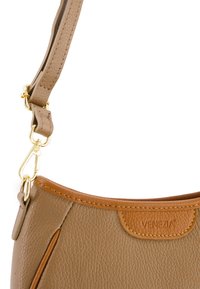 Tote aus tanfarbenem Leder mit strukturiertem Oberflächenfinish, goldfarbener Hardware, einem abnehmbaren Tragegurt und einem kontrastierenden braunen Lederakzent an der Oberseite.