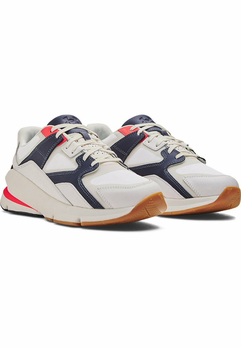 Zapatillas deportivas blancas con acentos en azul marino y rojo, que cuentan con una suela texturizada, paneles de malla y un diseño curvado para mayor soporte.