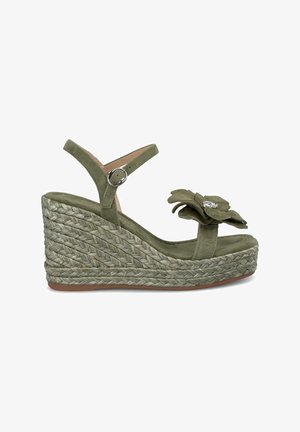 Sandalo wedge in suede verde con piattaforma in juta intrecciata, dotato di un accento floreale sulla cinghia della punta e di una cinghia regolabile alla caviglia.