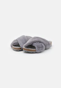 Chaussons à glissière en fausse fourrure grise avec design à lanières croisées et semelle semblable au liège. Texture douce, bout ouvert, et intérieur moelleux pour le confort.