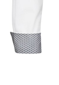 Manica di camicia bianca con polsino blu e grigio a motivo, caratterizzato da un design geometrico e una consistenza morbida, che mette in evidenza il contrasto tra i tessuti.