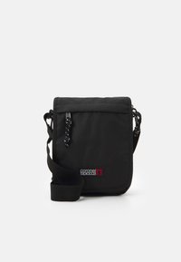 Bolso cruzado negro hecho de tela duradera, con cierre de solapa, correa ajustable y un parche de logo en colores contrastantes.