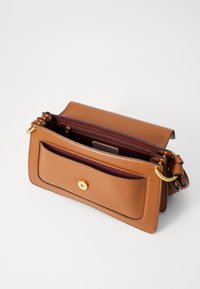 Brown leather handbag with a gold snap closure, interior zip pocket, and adjustable shoulder strap. Smooth texture and rectangular shape.