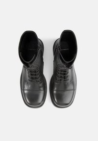 Black leather ankle boots with a smooth finish, lace-up design, side zippers, and round toes. Features a textured upper and flat soles.