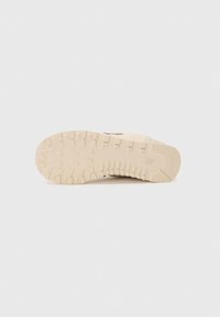Light beige sneaker sole with deep tread pattern and New Balance logo on the heel, shown against a plain white background.